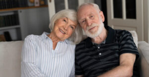 Casal de idosos sorrindo em casa, representando o objetivo de garantir a melhor aposentadoria com planejamento previdenciário